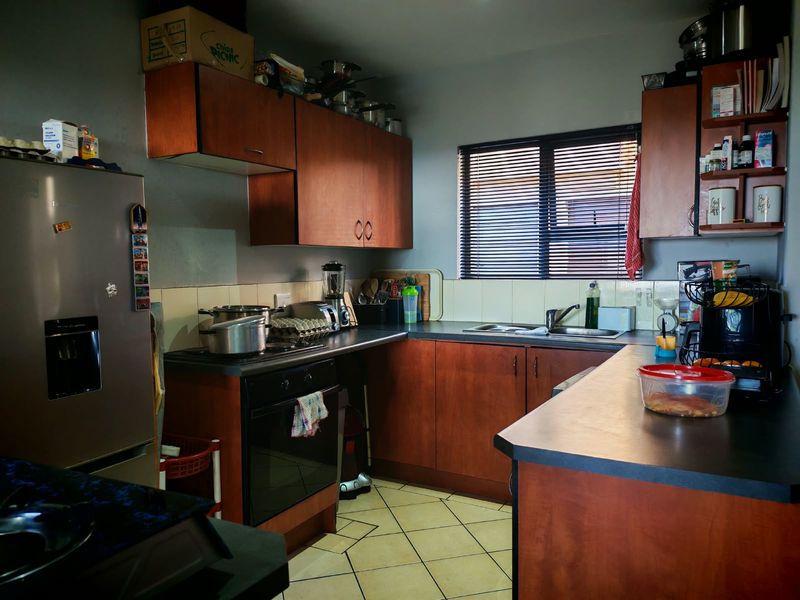 A functional kitchen featuring wood-finish cabinetry, laminate countertops, a built-in oven, and tiled flooring, offering a practical layout for daily meal preparation.