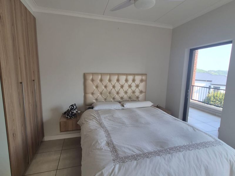A well-maintained bedroom featuring built-in cupboards, tiled flooring, a ceiling fan, and direct access to a private balcony.