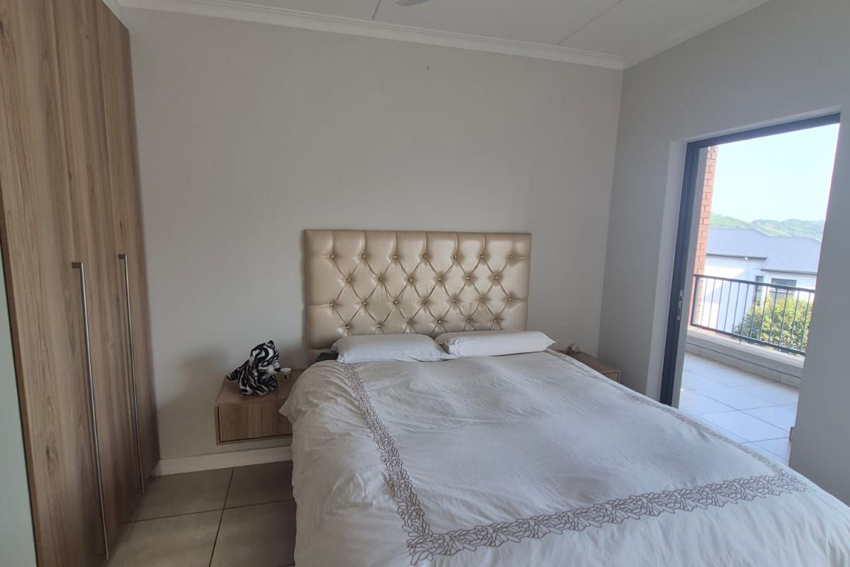 A well-maintained bedroom featuring built-in cupboards, tiled flooring, a ceiling fan, and direct access to a private balcony.