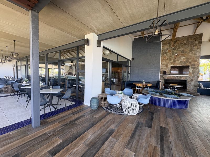 Spacious covered patio featuring a stone fireplace, tiled flooring, and a built-in water feature, offering a seamless transition between indoor and outdoor living areas.