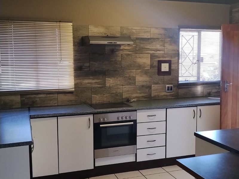 A functional kitchen featuring white cabinetry, a built-in oven with hob, tiled splashback, and timber ceiling finishes.