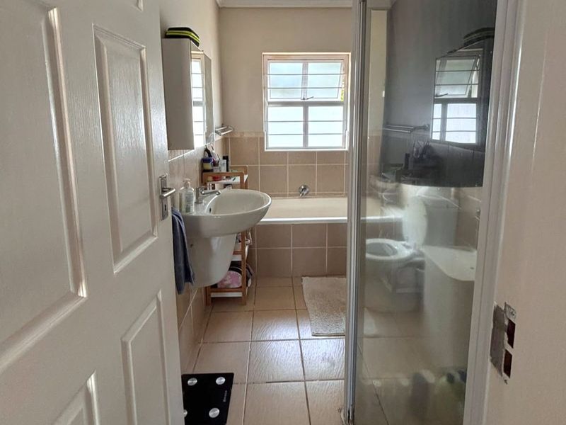 A functional bathroom featuring a pedestal basin, a built-in bathtub, and a separate shower enclosure with tiled finishes throughout.