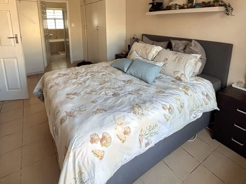 A functional bedroom featuring built-in cupboards, tiled flooring, and direct access to an en-suite bathroom.