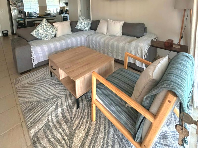 Open plan living area featuring tiled flooring and a connected kitchen space with built-in cabinetry and countertops.