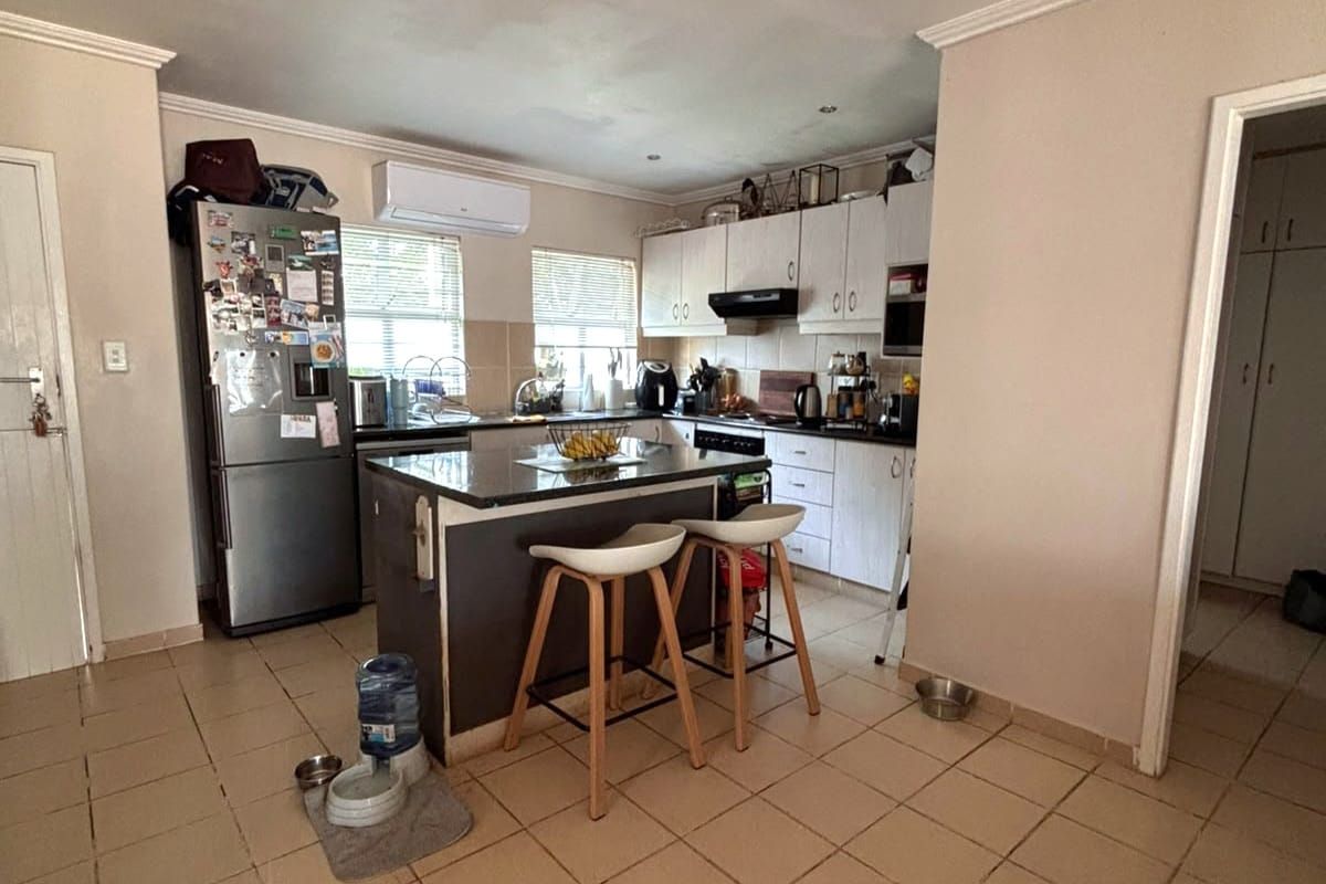 Functional kitchen featuring a central island with granite countertops, ample built-in cabinetry, and a wall-mounted air conditioning unit.