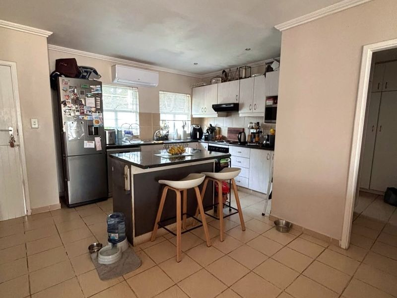 Functional kitchen featuring a central island with granite countertops, ample built-in cabinetry, and a wall-mounted air conditioning unit.