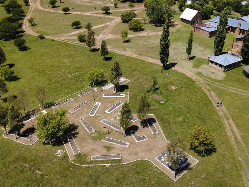 Aerial view of a farm property featuring a miniature golf course set within expansive grassy grounds and surrounding farm buildings.