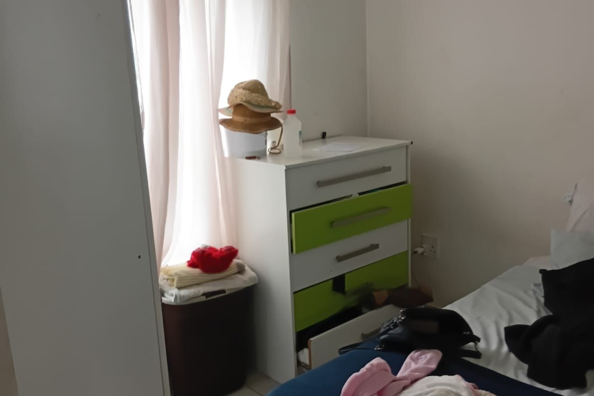 A bedroom featuring tiled flooring and a window with a curtain rod, providing a functional space for rest.