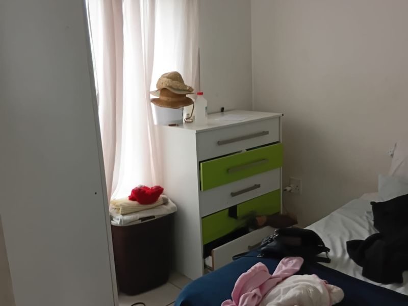 A bedroom featuring tiled flooring and a window with a curtain rod, providing a functional space for rest.