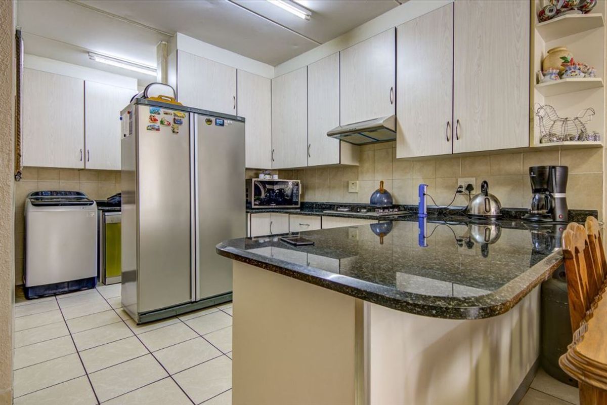 Functional kitchen featuring granite countertops, ample laminate cabinetry, tiled backsplash, and a convenient breakfast bar, providing a practical layout for daily meal preparation.