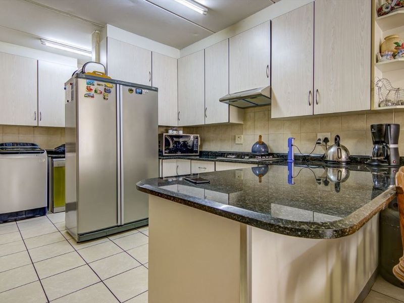 Functional kitchen featuring granite countertops, ample laminate cabinetry, tiled backsplash, and a convenient breakfast bar, providing a practical layout for daily meal preparation.