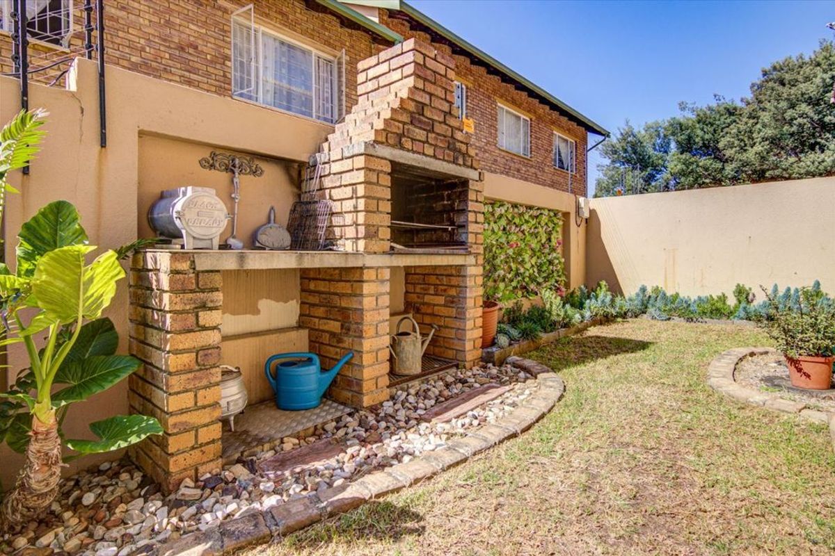 Rear garden area featuring a built-in brick braai, established garden beds, and a perimeter wall, providing a functional outdoor entertainment space.