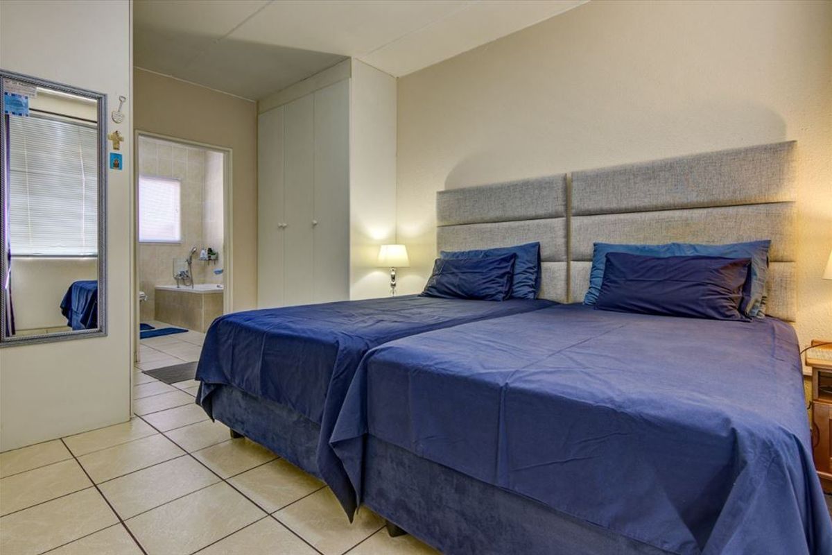 A bedroom featuring tiled flooring, built-in cupboards, and direct access to an en-suite bathroom.