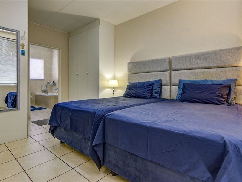 A bedroom featuring tiled flooring, built-in cupboards, and direct access to an en-suite bathroom.