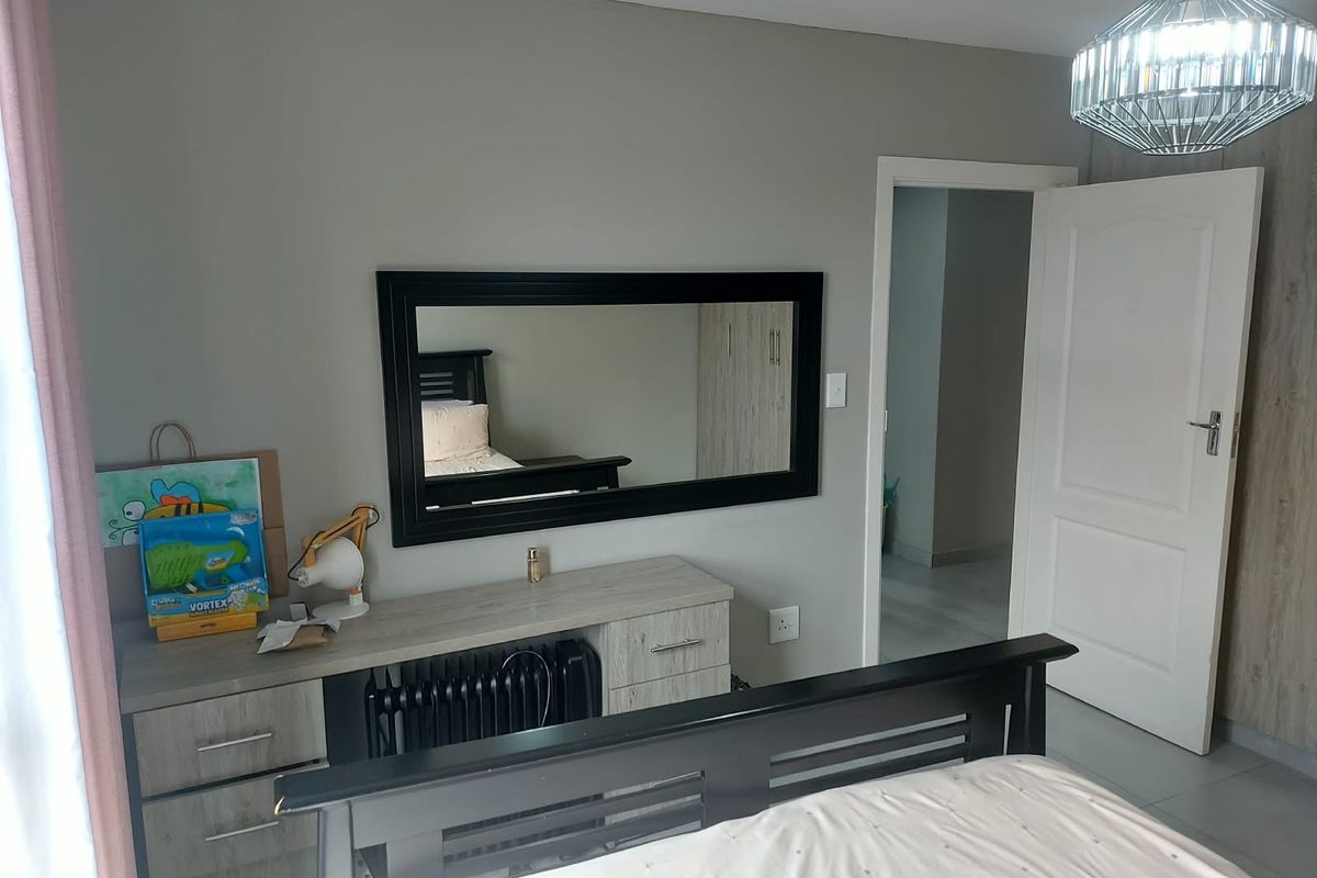 A well-maintained bedroom featuring neutral wall tones, tiled flooring, built-in cabinetry, and a modern pendant light fixture.