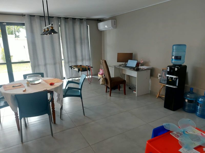 A bright living area featuring large sliding glass doors, neutral tiled flooring, and a wall-mounted split-system air conditioner.