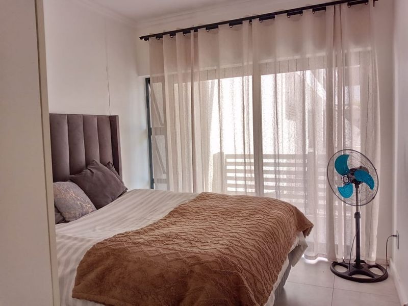 A well-lit bedroom featuring tiled flooring and a large sliding glass door that provides access to an outdoor area.