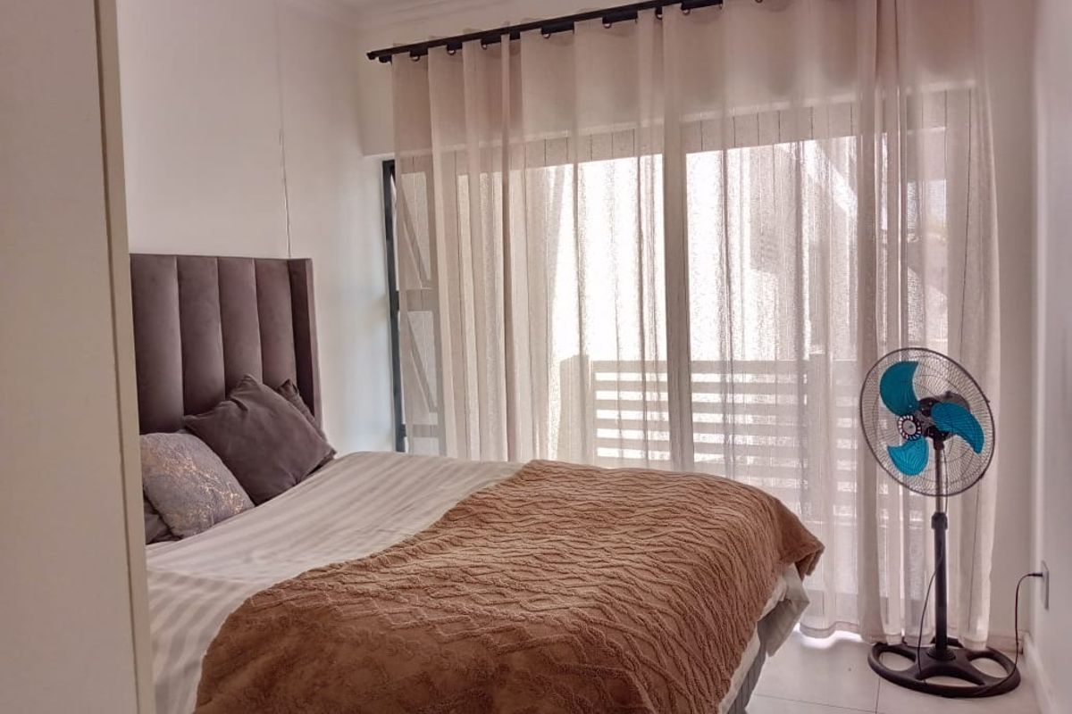 A well-lit bedroom featuring tiled flooring and a large sliding glass door that provides access to an outdoor area.
