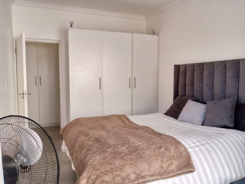 A well-maintained bedroom featuring neutral tiled flooring, built-in cupboards, and decorative cornice detailing.