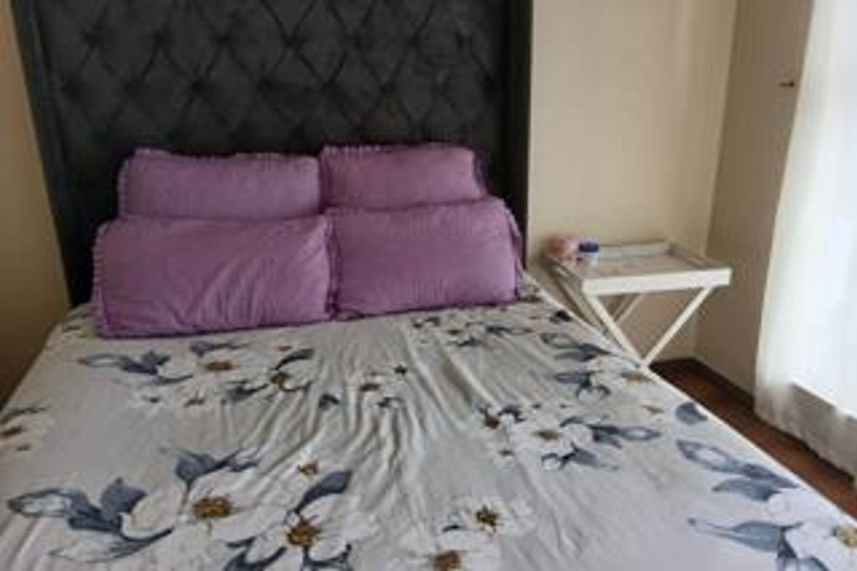 A bedroom featuring laminate flooring and a neutral wall finish, providing a functional space for rest.
