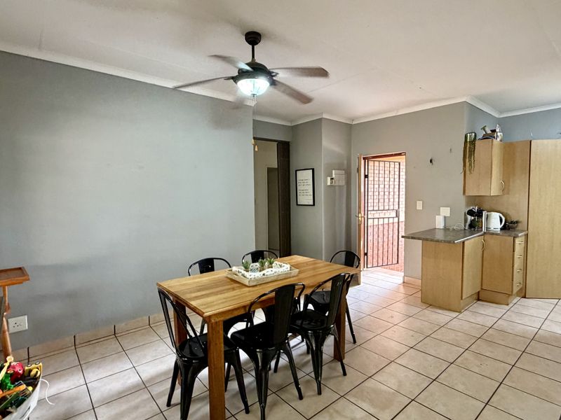 Open plan living and dining area featuring tiled flooring, a ceiling fan, and a functional kitchen with built-in cabinetry and laminate countertops.