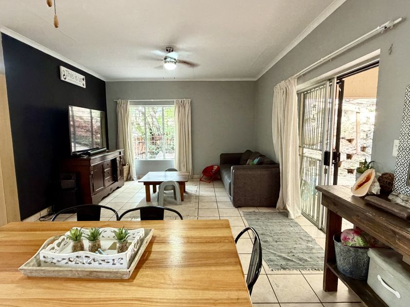 Open-plan living and dining area featuring tiled flooring, a ceiling fan, and sliding glass doors providing access to the outdoor space.
