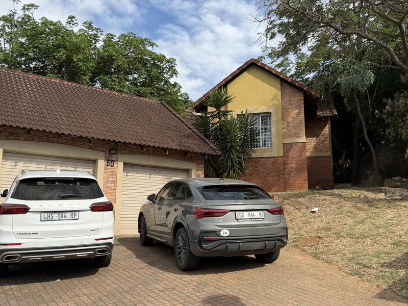 Front elevation of a brick house featuring a double garage, tiled roof, and a paved driveway.