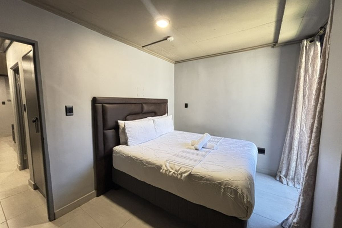 A functional bedroom featuring tiled flooring and an exposed ceiling design, providing a neutral base for interior styling.