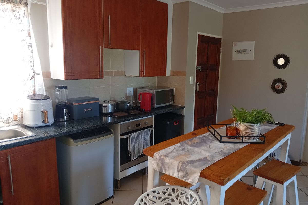 A functional kitchen featuring wood-finish cabinetry, granite countertops, a built-in oven and hob, and tiled flooring, offering a practical layout for daily use.