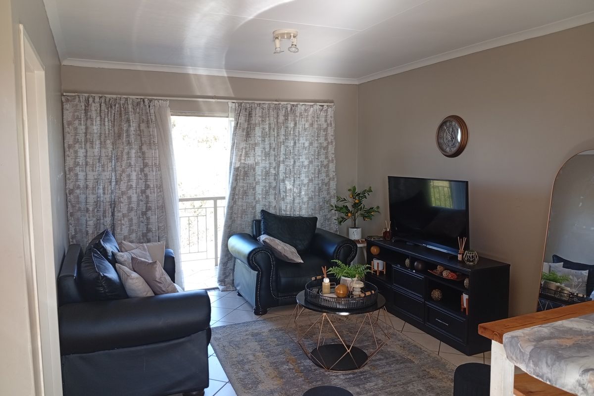 A comfortable living room featuring tiled flooring and a sliding glass door that provides access to an outdoor balcony area.