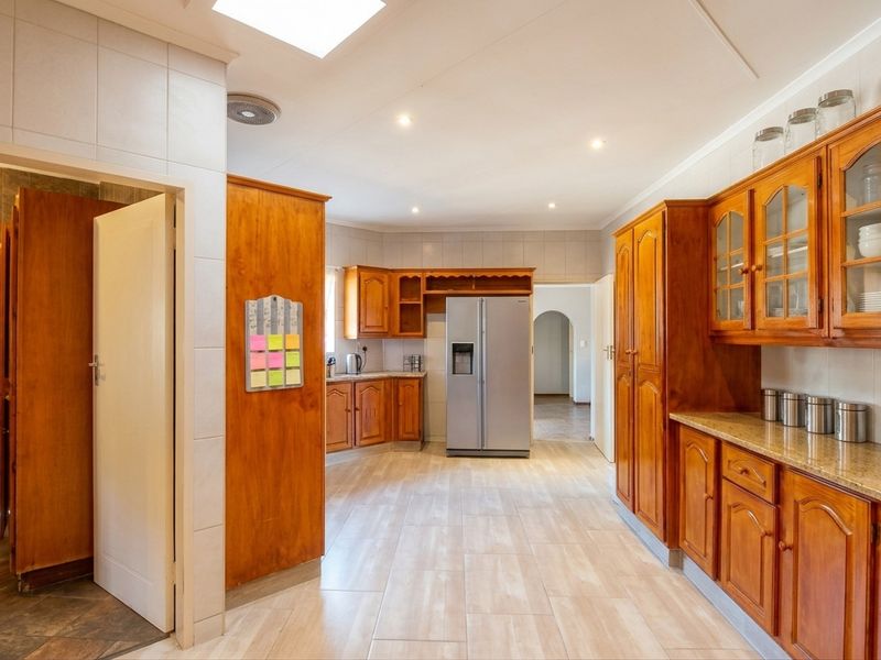 Spacious kitchen featuring extensive wooden cabinetry, granite countertops, tiled flooring, and a skylight, offering a functional layout with ample storage space.
