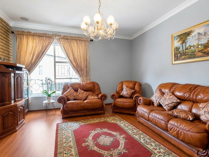 A comfortable living room featuring laminate flooring, a brick feature wall, and classic ceiling cornice detailing.