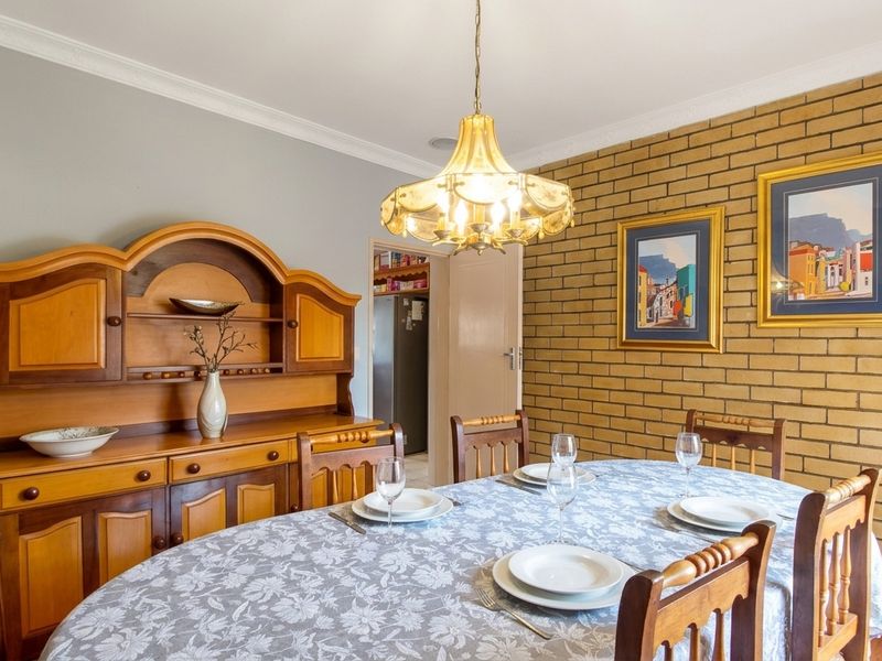 A dining room featuring an exposed brick feature wall, decorative coving, and a central pendant light fixture.