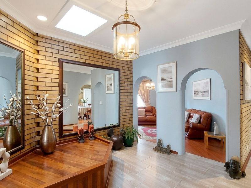 Spacious entrance hall featuring a brick feature wall, skylight, and elegant archways leading into the living areas with tiled flooring throughout.