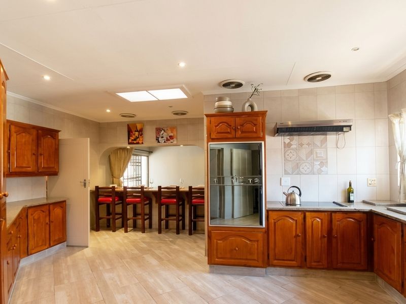 Spacious kitchen featuring traditional wooden cabinetry, built-in oven, extractor fan, and a breakfast bar area with tiled flooring and neutral wall finishes.