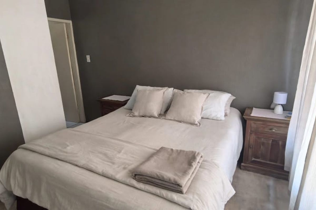 A neutrally decorated bedroom featuring dark accent walls and a simple layout, offering a comfortable and quiet sleeping space.