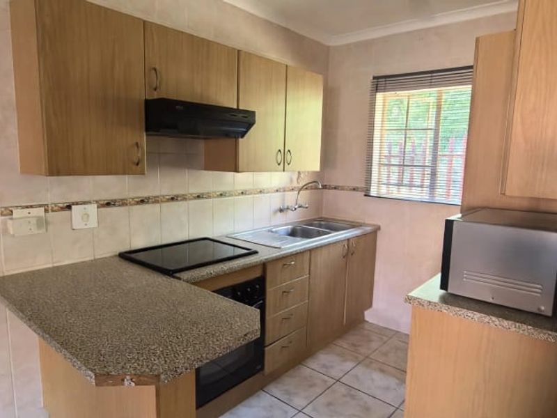 A functional kitchen featuring laminate cabinetry, granite countertops, built-in oven, electric hob, and tiled backsplash with a window for natural light.