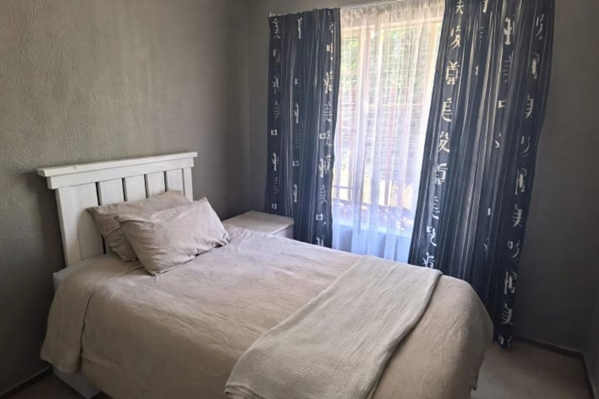 A compact bedroom featuring neutral wall finishes and a window with curtain rails, providing a functional space for rest.