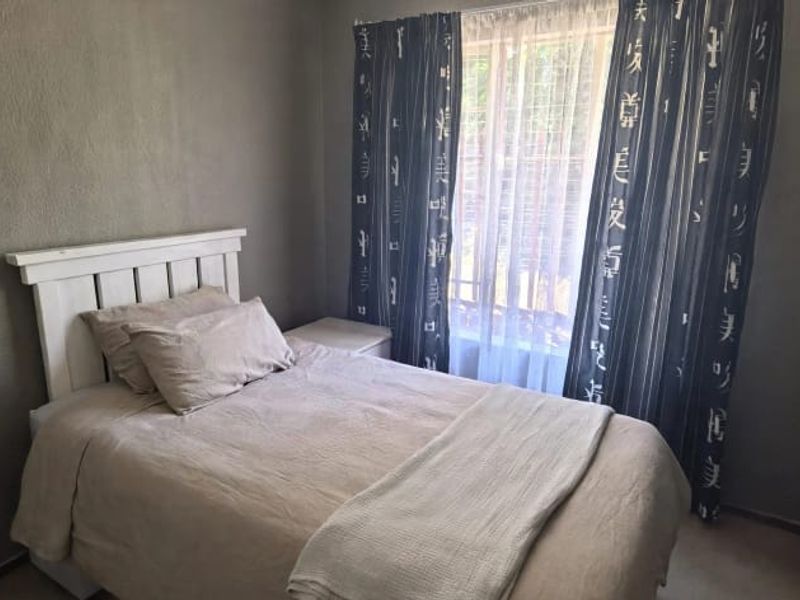 A compact bedroom featuring neutral wall finishes and a window with curtain rails, providing a functional space for rest.