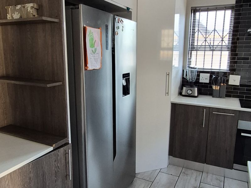 Modern kitchen featuring two-tone cabinetry, subway tile backsplash, and wood-look tiled flooring with integrated appliances.