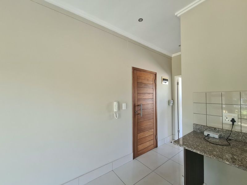 A clean and well-maintained entry area featuring tiled flooring, a solid wooden door, and a granite-topped counter space.