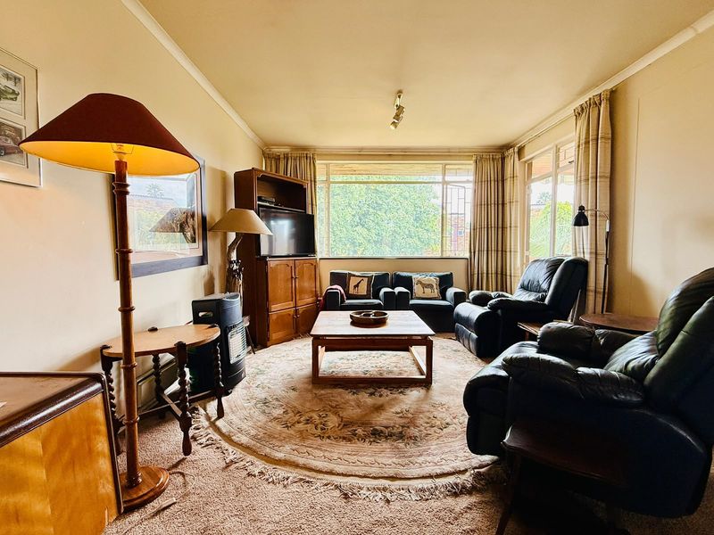 A comfortable living room featuring large windows that provide ample natural light and carpeted flooring throughout.