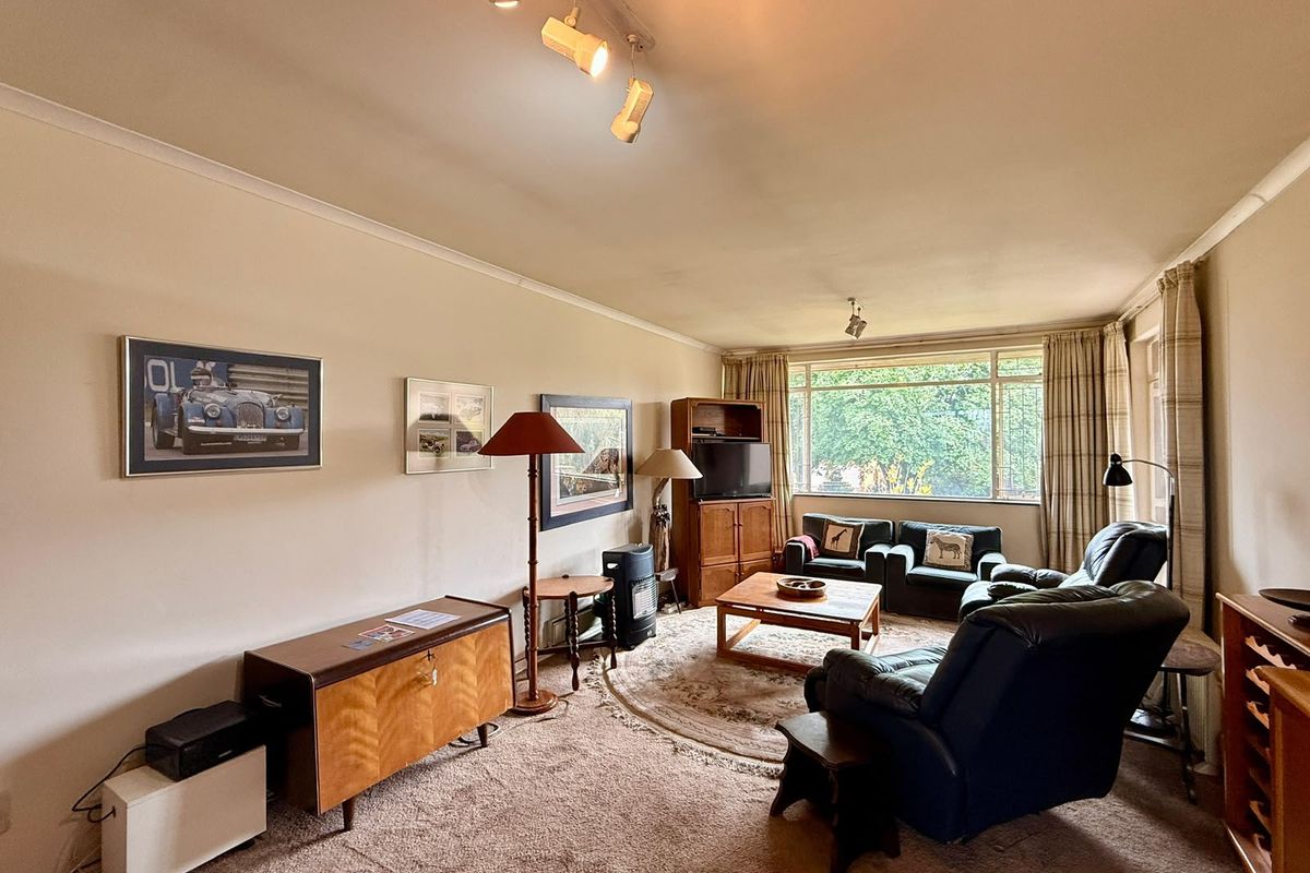 A spacious living room featuring large windows, neutral walls, and carpet flooring, offering a comfortable and well-lit area for relaxation.