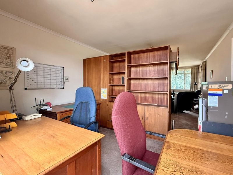 A home office space featuring built-in wooden shelving and carpeted flooring, offering a functional layout for a workspace.