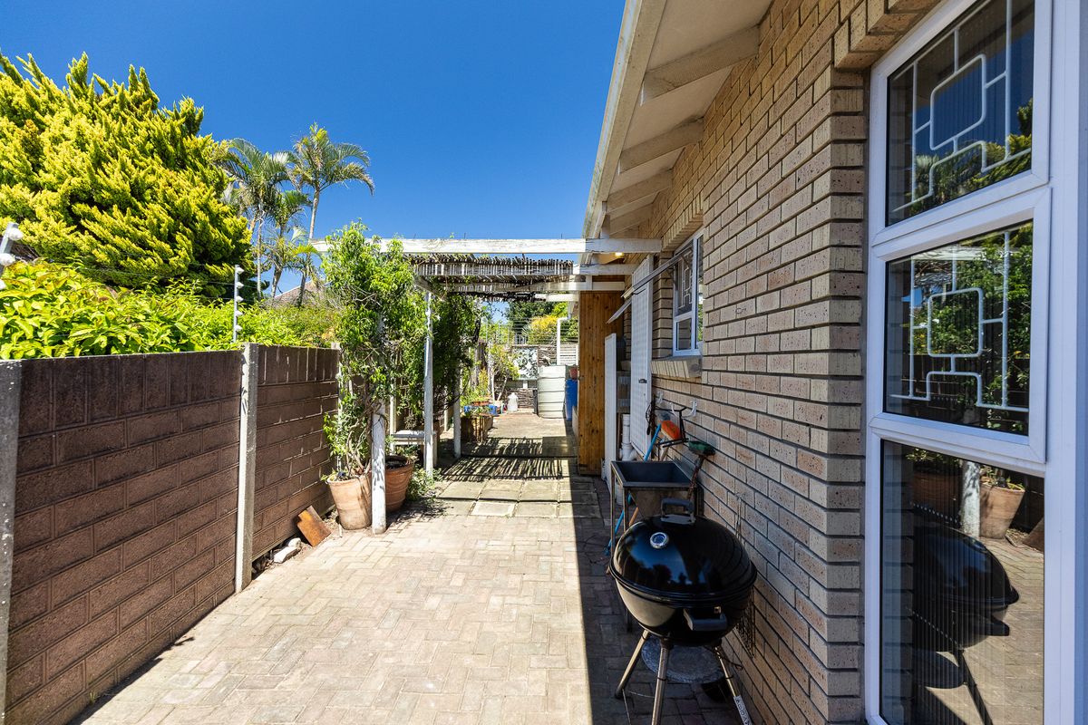 A side exterior area featuring brick paving, a timber pergola, and a boundary wall, providing a functional outdoor space for the townhouse.