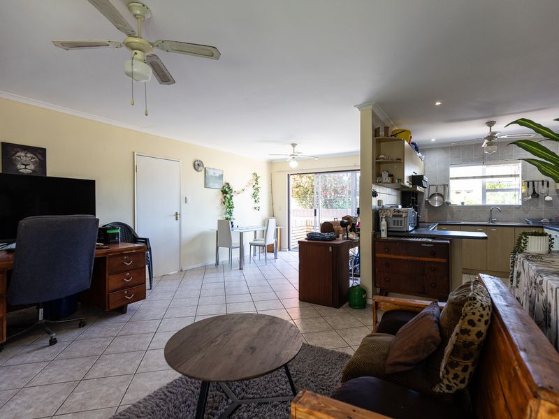 Open-plan living and kitchen area featuring tiled flooring, ceiling fans, and direct access to the outdoor patio through sliding glass doors.