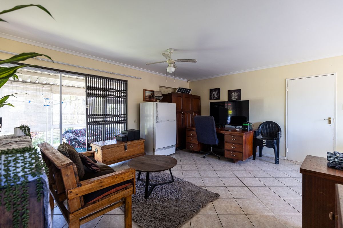 Spacious living area featuring tiled flooring, a ceiling fan, and large sliding glass doors providing access to the outdoor patio area.