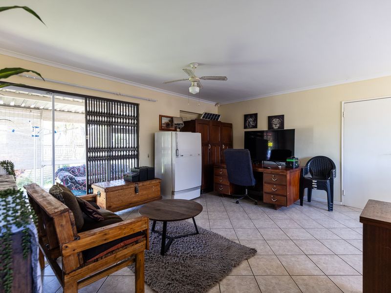 Spacious living area featuring tiled flooring, a ceiling fan, and large sliding glass doors providing access to the outdoor patio area.