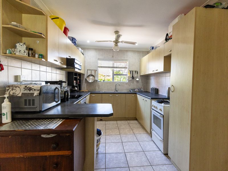 A functional kitchen featuring laminate cabinetry, dark countertops, tiled flooring, and a freestanding oven, offering a practical layout with ample storage space.