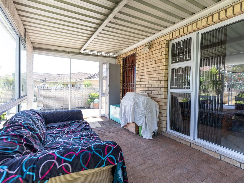 A covered patio area featuring brick paving, brick walls, and sliding glass doors, providing a functional outdoor living space.